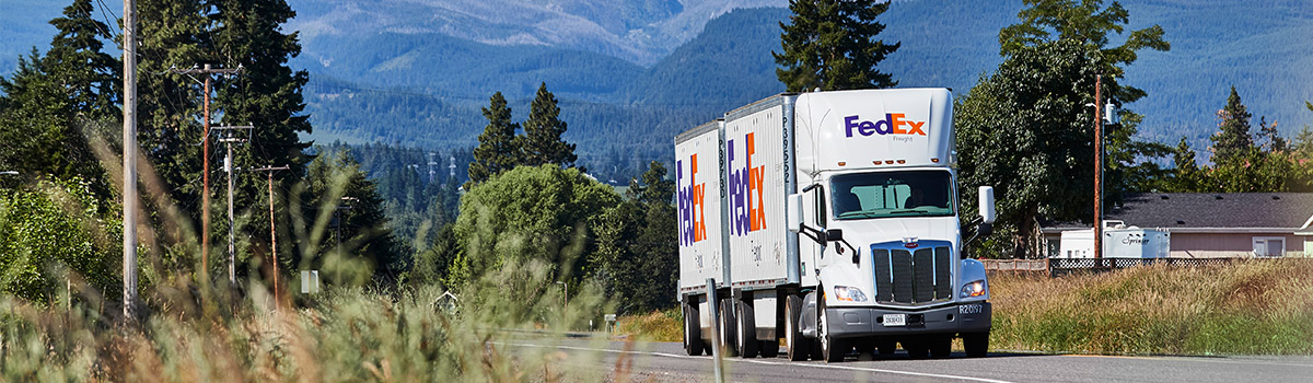 A FedEx Freight truck drives down a road.