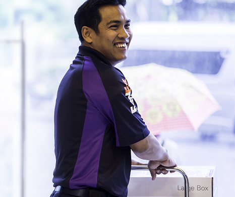 A male FedEx courier pushing a FedEx box on a dolly