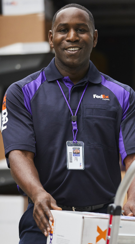 A male FedEx Express courier smiling with a FedEx box