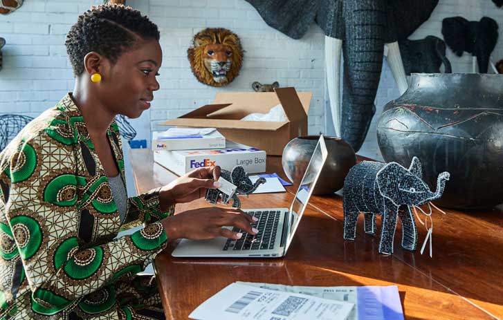 A woman working on a laptop with an ornamental elephant on the table.