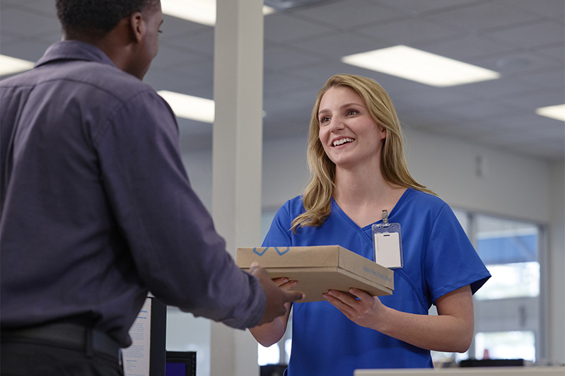 Man hands package to woman in scrubs
