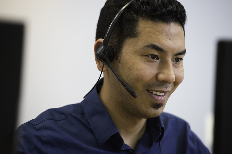 man working on computer with a headset 