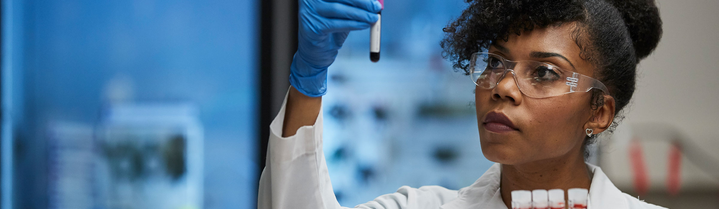 Lab tech looking at sample as she holds it up