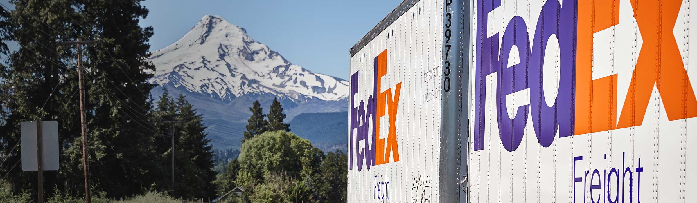 FedEx Freight truck driving with snow-covered mountain in background