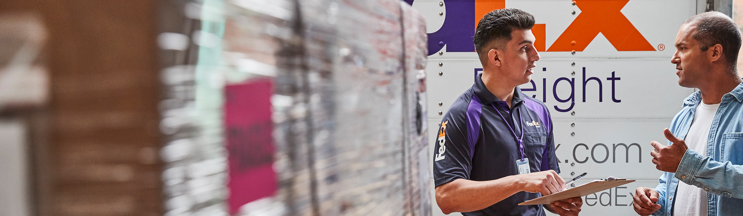 FedEx Freight driver and a man talking near a FedEx Freight® box.