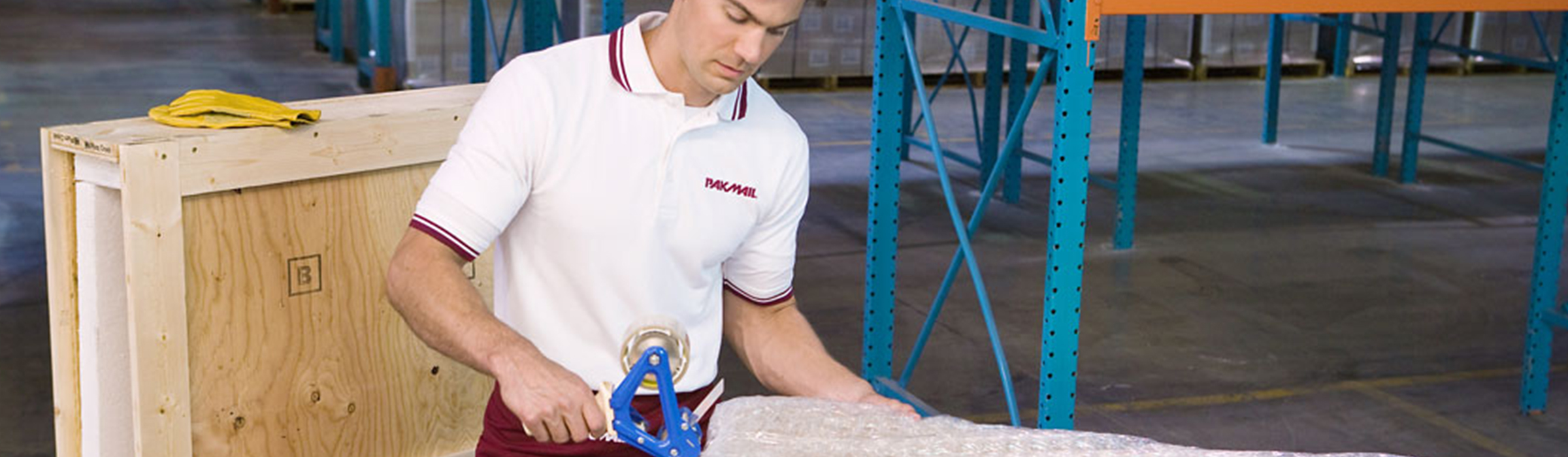 Pak Mail worker taping a large item for shipping.