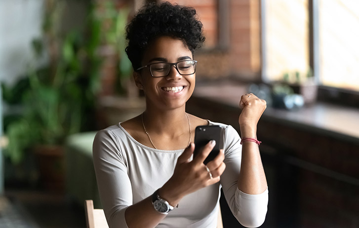Person pumping their fist in excitement while looking at their mobile phone.