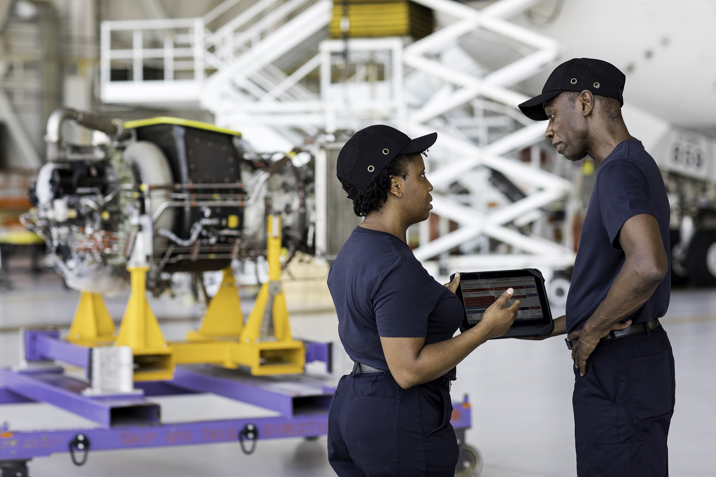 Team members reviewing tablet information in air hanger