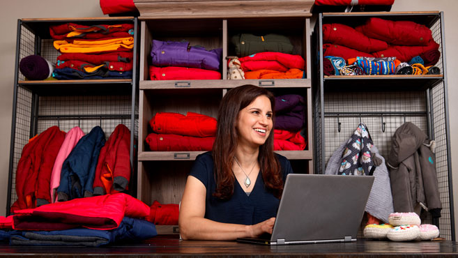 Woman on laptop in coat inventory room