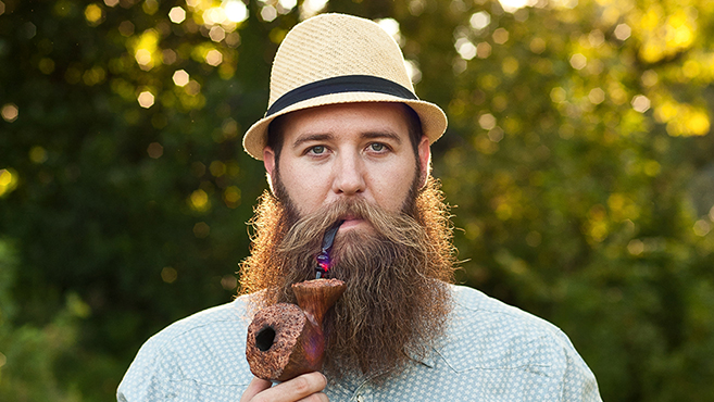 Ryan Lane, creator of Dream Beard, poses with a smoking pipe in his mouth