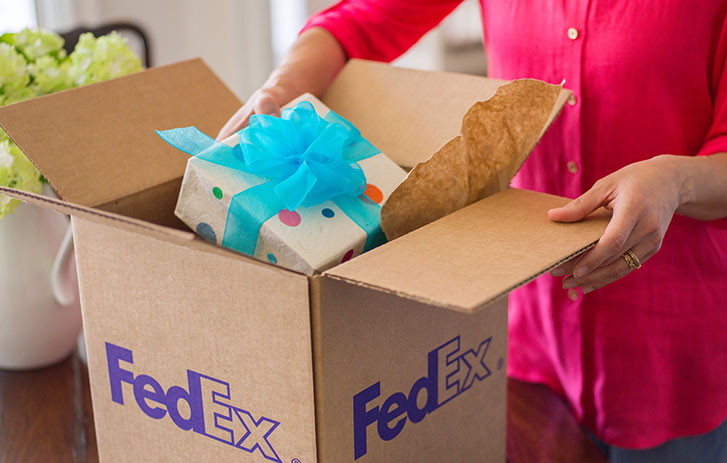 woman putting gift in fedex brown box