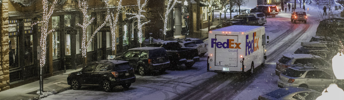 fedex ground truck driving through snowy downtown street at night