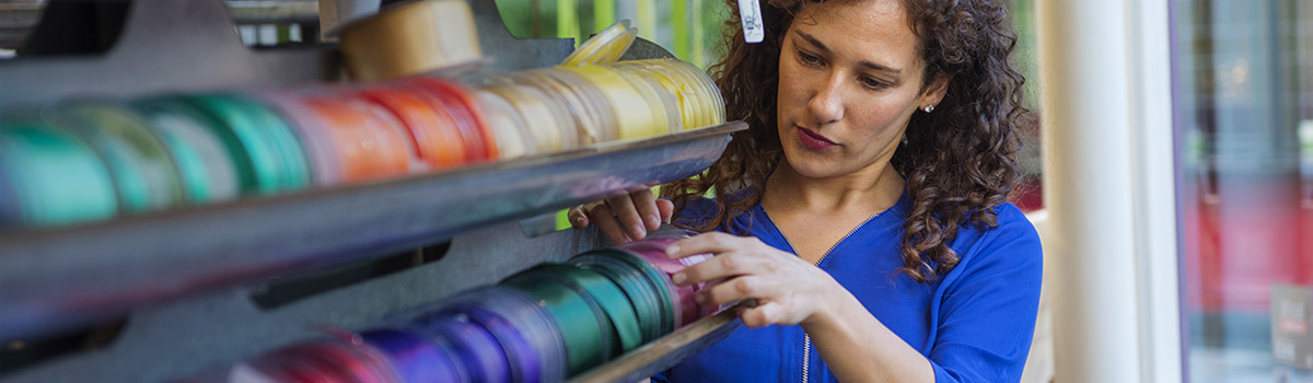 Female small business owner picking ribbon for holiday shipping