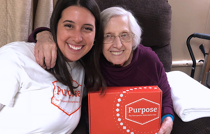 A photo of Purpose, The Therapeutic owner with a patient smiling and holding branded box.