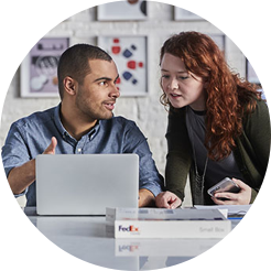 A man and a woman at a computer with a box.