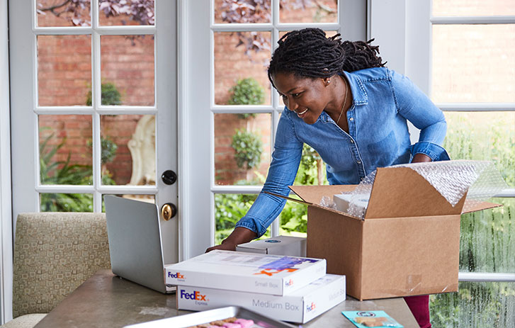 woman packing products into fedex boxes
