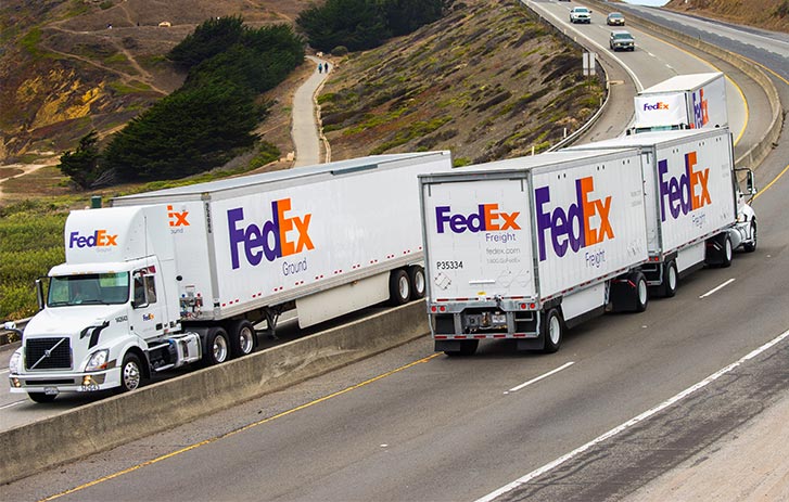 two fedex semi trucks passing each other on highway