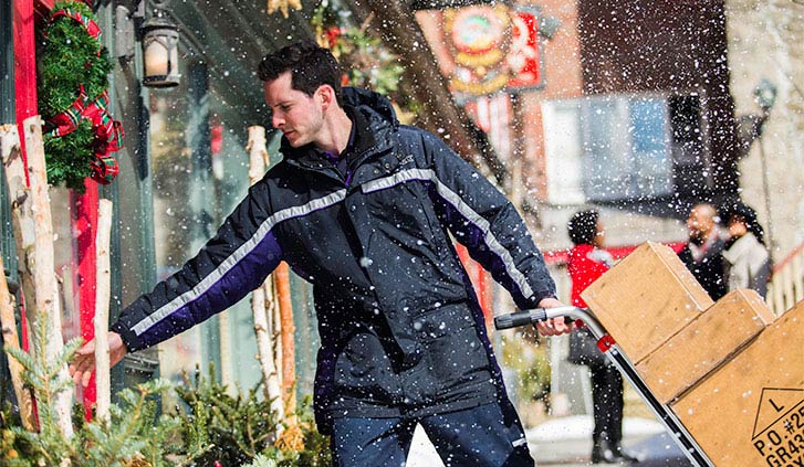 FedEx courier pushing large package on moving dolly