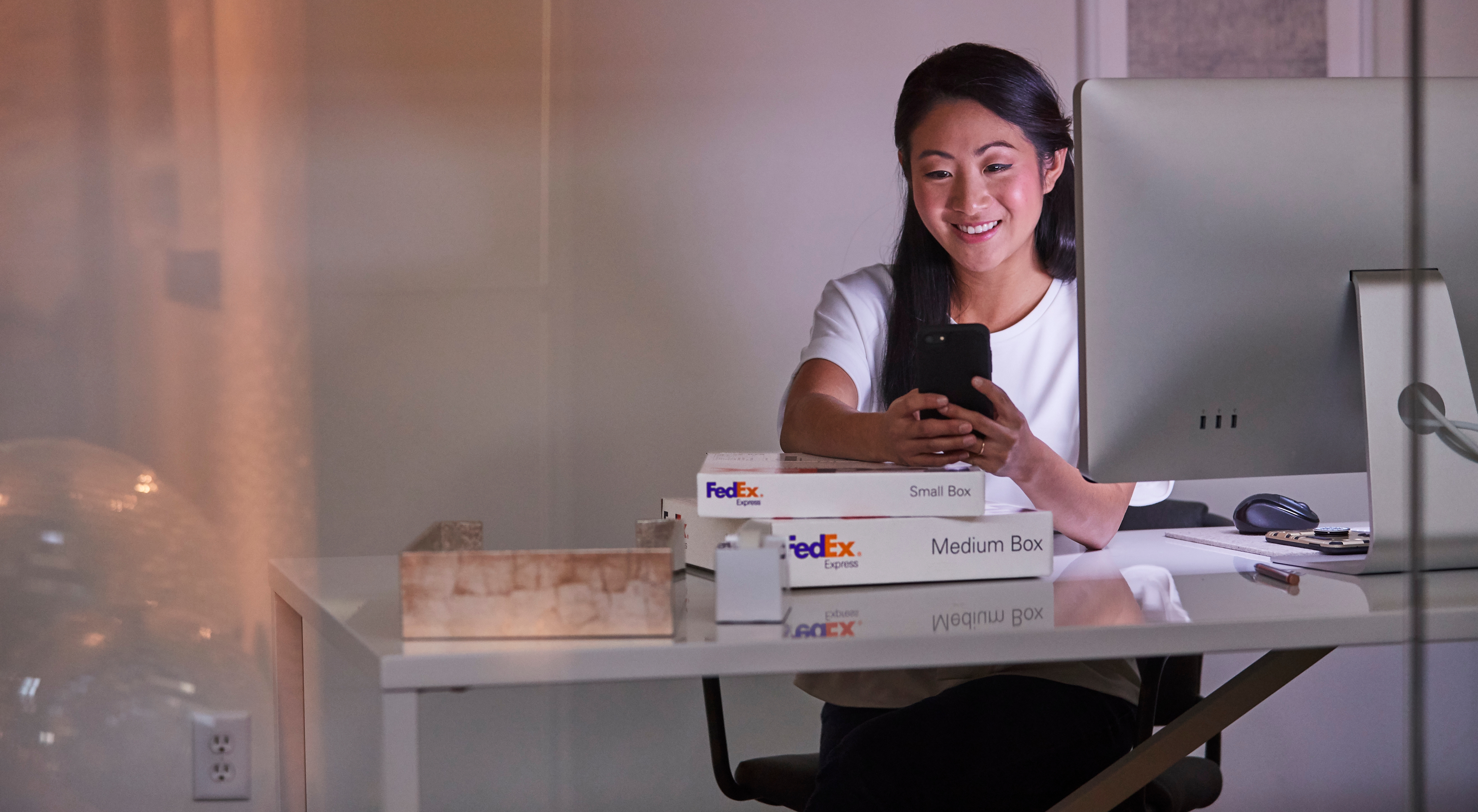 femme avec un cellulaire et des colis FedEx