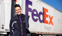 Photo of female truck driver standing by truck