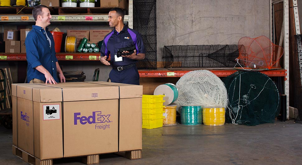 A FedEx driver talking to a warehouse worker about a pallet of freight