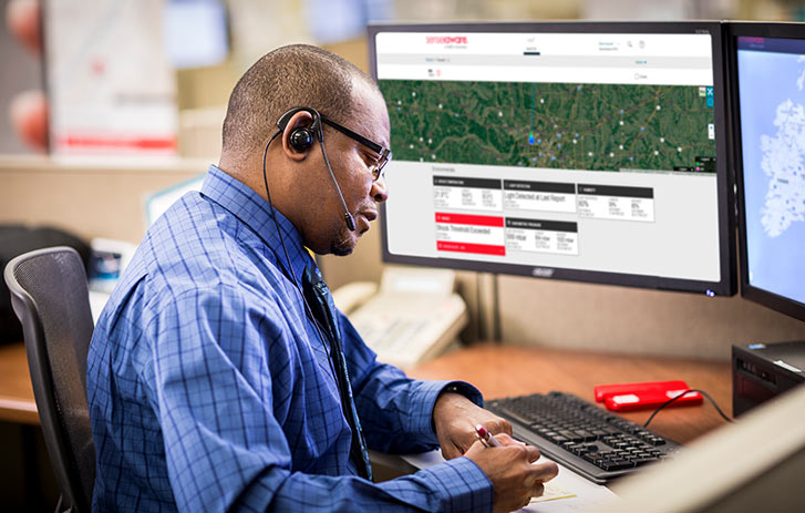 A phone operator talking to someone in front of two monitor screens