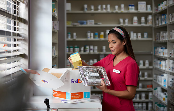 A pharmacist technician opening a box of medical supplies