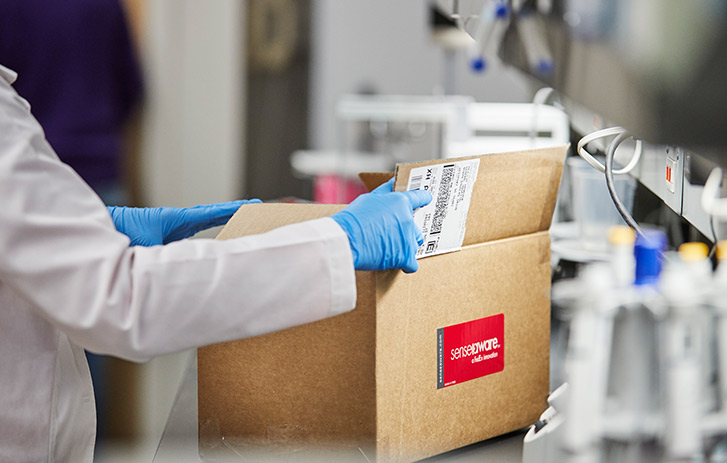 A lab technician opening a shipping box with medical supplies in it