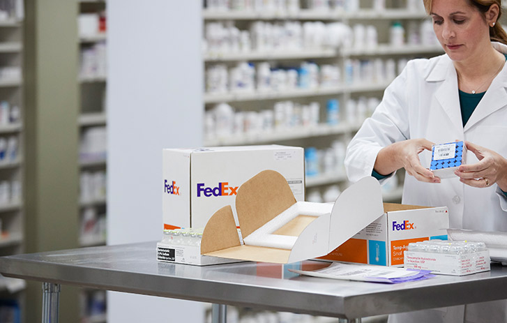 A pharmacy technician picking up temperature-controlled supplies out of shipping box