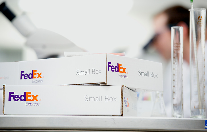 A stack of white shipping boxes on a lab table
