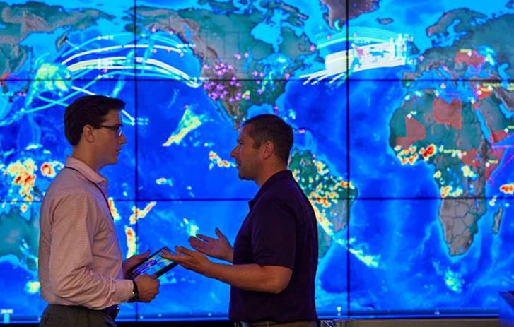 Men talking in front of large digital weather map