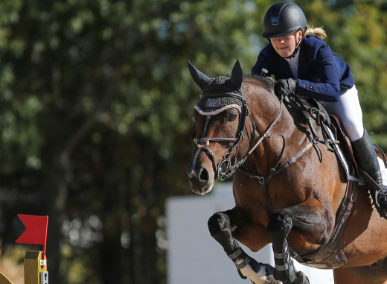 A female equestrian riding a horse of a competition course