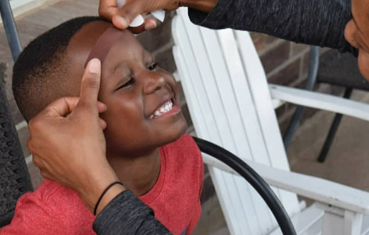 Child getting a band aid on his forehead
