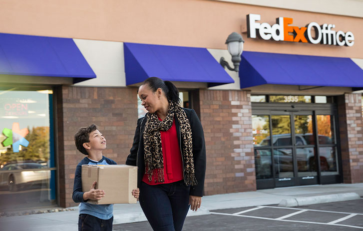 Woman with son picking up package held at FedEx store