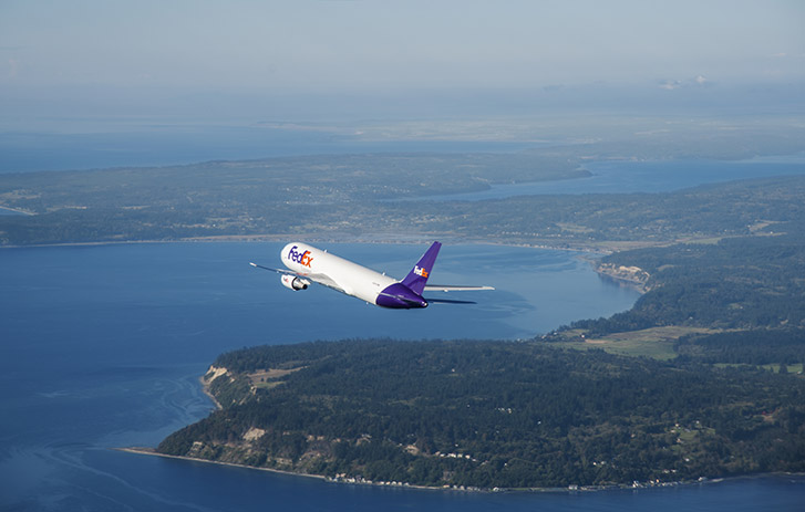 FedEx branded airplane flying over an international island.