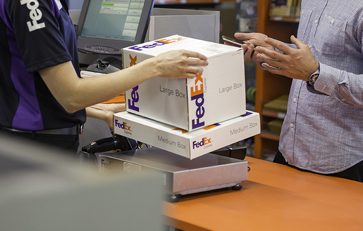 FedEx employee holding two FedEx Express boxes.