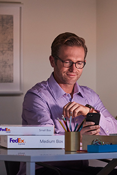 A man looking at a smart phone at a work desk