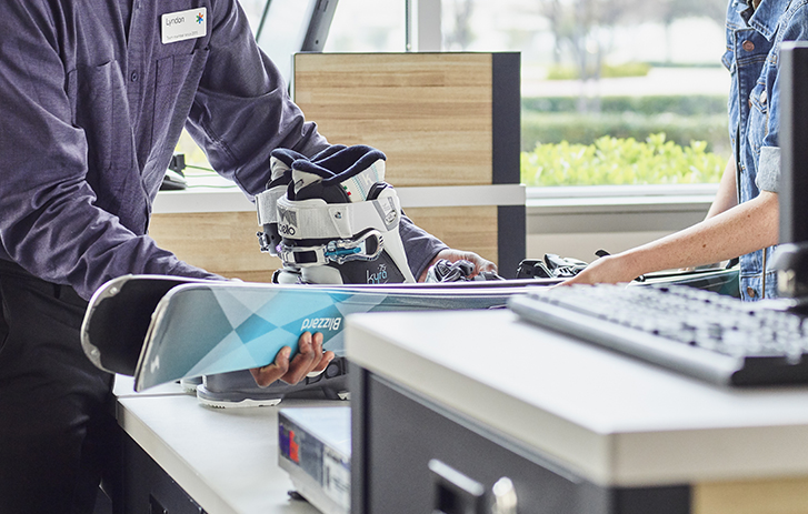 Image of a customer handing over ski's to a FedEx team member to be packed and shipped.