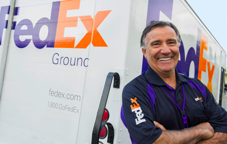 Smiling courier next to FedEx Ground truck