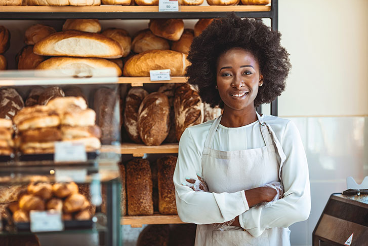 Female bakery owner standing in front of baked goods Female bakery owner standing in front of baked goods