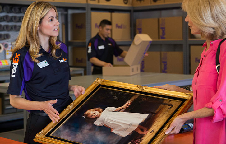 Woman bringing large framed picture to have shipped