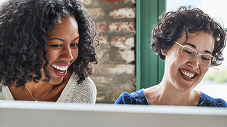 2 mujeres sonriendo a una computadora